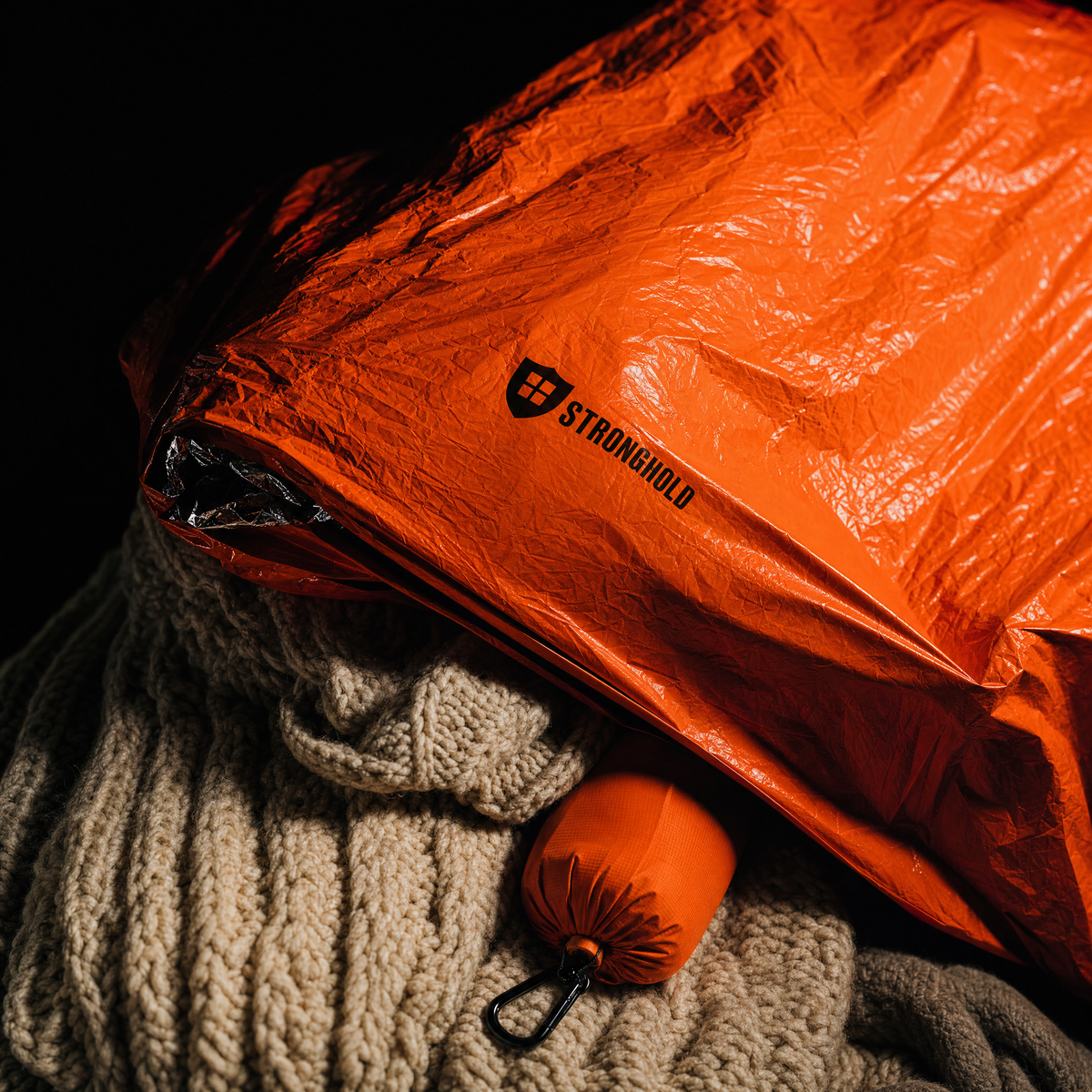 Orange emergency bivy over thick knitted wool blankets